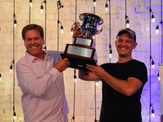 The 2022 Corporate Ping Pong Champions, Tom & Corey Hammerton from OSF, hoist the championship cup above their heads.